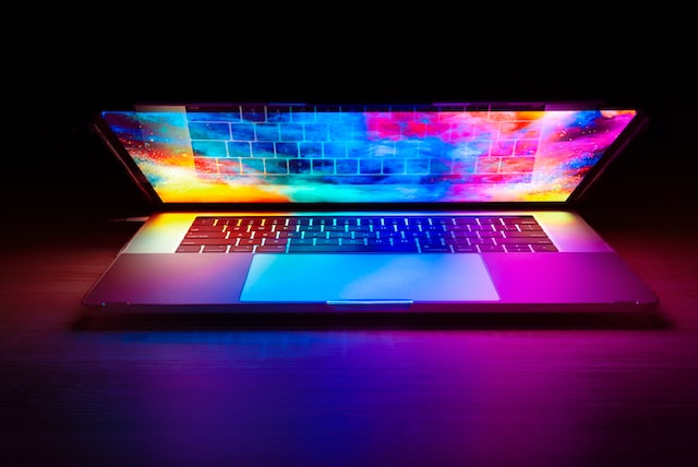 This is a picture of a laptop that is slightly open emitting a colorful light.