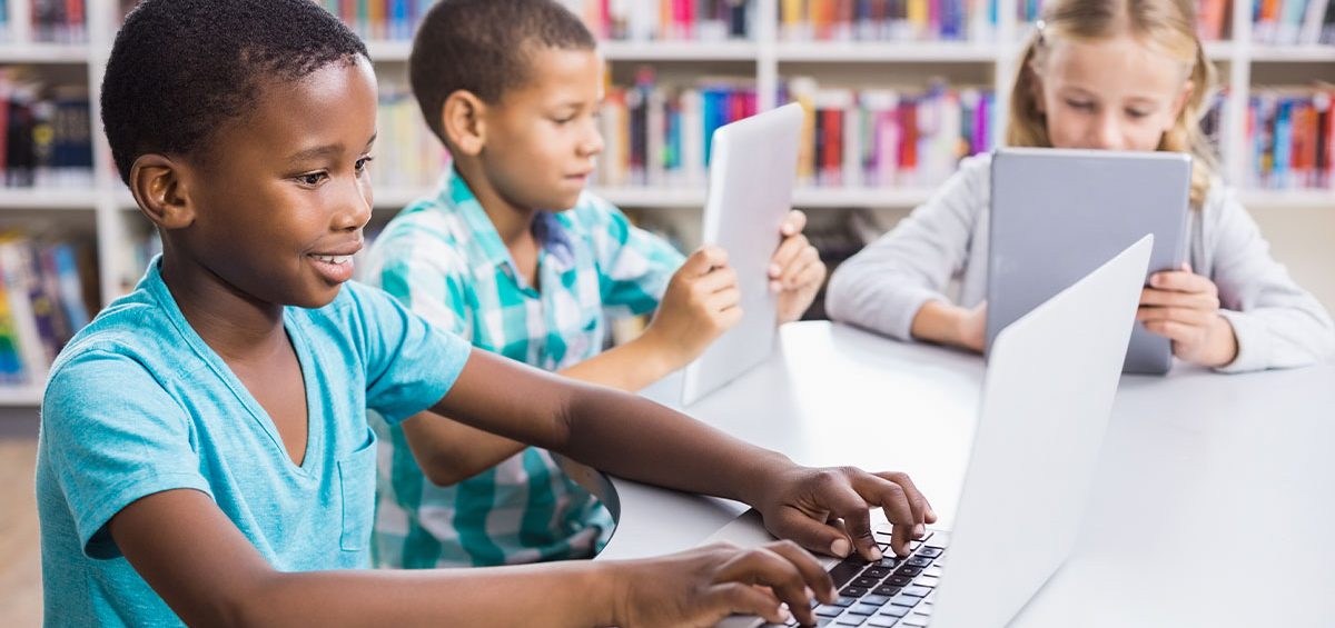 There are children, two boys and one girl. They each are using a laptop in a library.